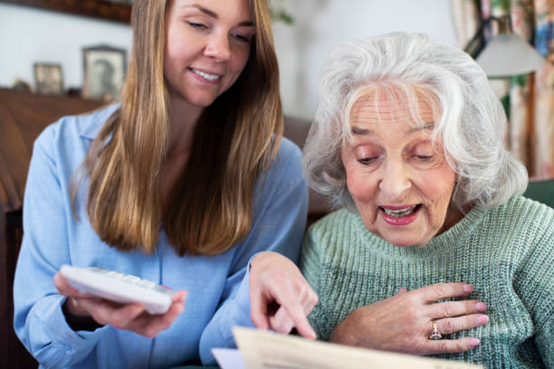 mujer ayudando a vecinos mayores con facturas y papeleo - care community 80 plus years cheerful fotografías e imágenes de stock