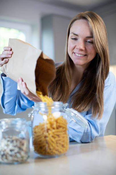istock Woman Pouring Pasta From Plastic Free Packaging Paper Bag Into Storage Jar 1178321525