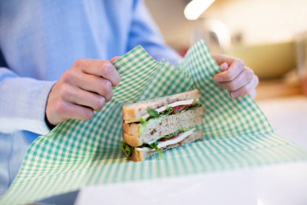 Close Up Of Woman Wrapping Sandwich In Reusable Environmentally Friendly Beeswax Wrap Close Up Of Woman Wrapping Sandwich In Reusable Environmentally Friendly Beeswax Wrap beeswax photos stock pictures, royalty-free photos & images