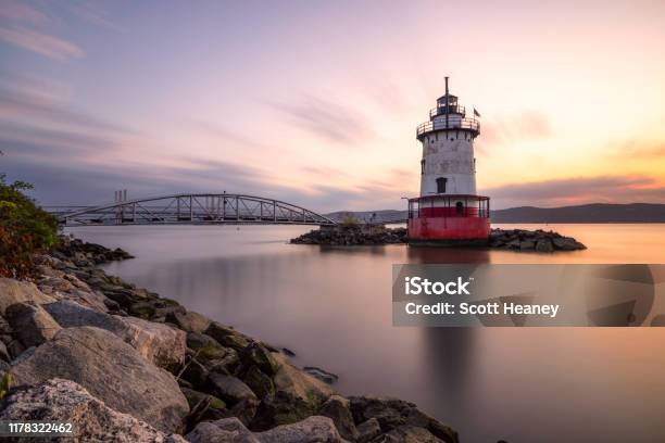Caisson Style Lighthouse Under Soft Golden Light With A Bridge In The Background Stock Photo - Download Image Now