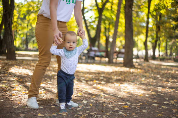 supporto insostituibile delle mamme - baby first steps autumn child foto e immagini stock