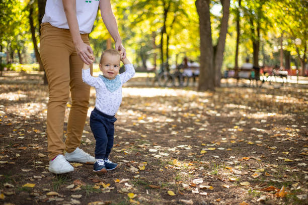 supporto insostituibile delle mamme - baby first steps autumn child foto e immagini stock