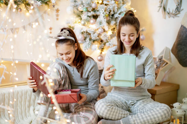 Teenage girls looking inside gift boxes and smiling stock photo