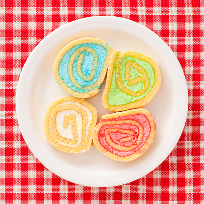 Top view of white dish with four rolls filled with creams of different colors