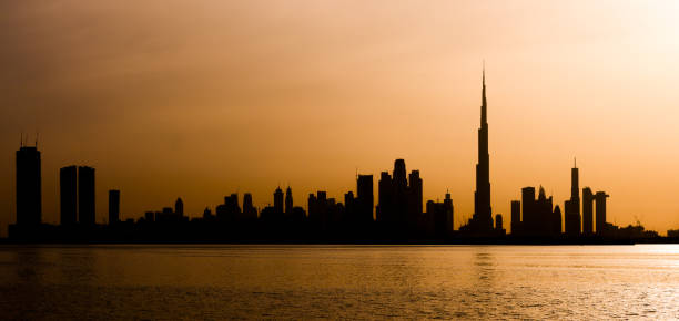 stunning view of the silhouette of the dubai skyline during a beautiful and dramatic sunset. - fog desert arabia sunset imagens e fotografias de stock