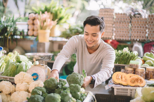 an asian malay vegetable retail owner arranging his vegetables getting ready for the business an asian malay vegetable retail owner arranging his vegetables getting ready for the business malay stock pictures, royalty-free photos & images