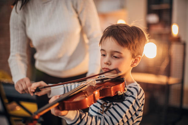 kleiner junge lehre, geige zu spielen - practicing music violin women stock-fotos und bilder