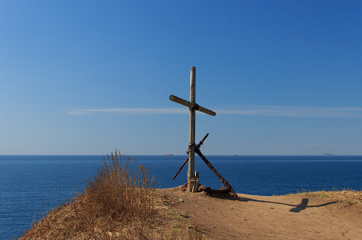 Monument in the form of a wooden cross and an old anchor, standing on a cliff on the edge of Cape Tobizin, Russian Island, Vladivostok.