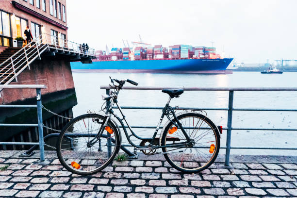 Embankment in the city of Hamburg, close-up of a bicycle on the background of a cargo ship moving in the bay.