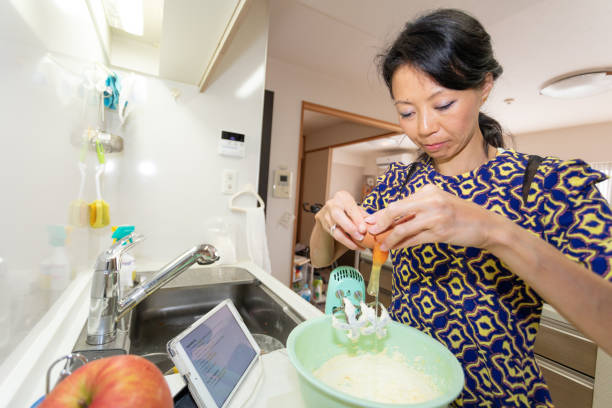 femme faisant le gâteau en utilisant l'appareil numérique - baking cake making women photos et images de collection