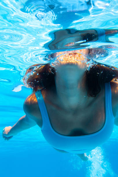 Underwater photo of a woman swimming in fresh clean water stock photo
