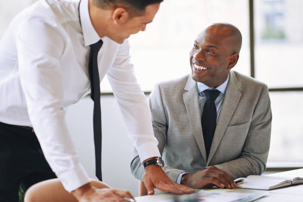 istock Two smiling businessmen discussing paperwork together in an office 1178342210