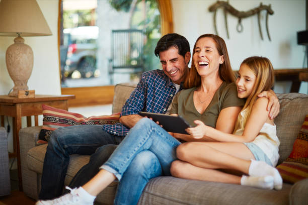 Parents and child streaming media content from a digital tablet. Lifestyle Spanish family in a luxury house family at home stock pictures, royalty-free photos & images
