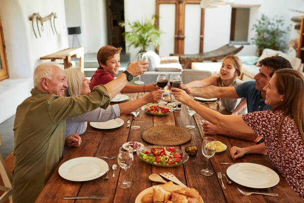 familia en casa comiendo juntos y celebrando. - los niños y los padres brindis bebidas mientras almuerza fotografías e imágenes de stock