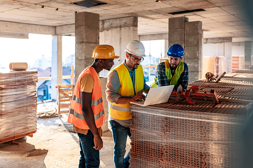 Engineer, architect and business man working on the engineering project at construction site. House building concept. Photo of young male architect engineer using laptop computer.