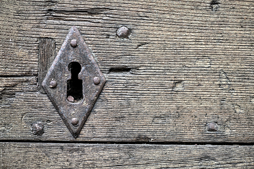 Detail of an old ancient wooden door with a beautiful iron knock handle. Close up.