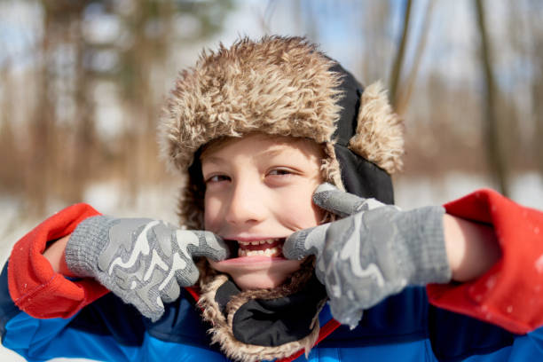 istock Portrait of a smiling boy being silly and pulling a face in fresh snow during wintertime 1178349996