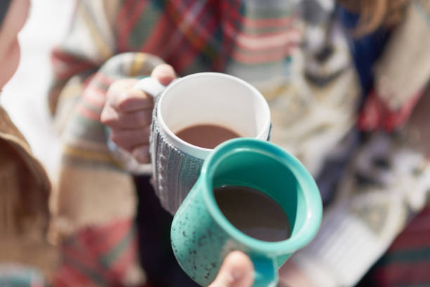 Couple in love enjoying a tender moment in fresh snow during wintertime and drinking hot chocolate together