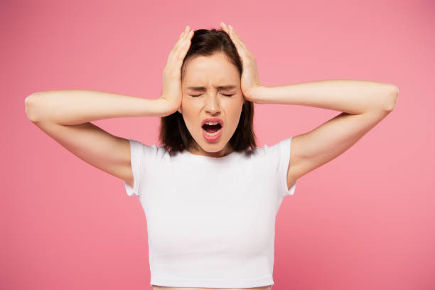 beautiful girl with hands on head and closed eyes screaming isolated on pink beautiful girl with hands on head and closed eyes screaming isolated on pink hands covering ears stock pictures, royalty-free photos & images