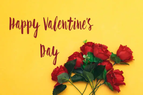 Photo of beautiful roses flowers  with happy valentine's day isolated on yellow background