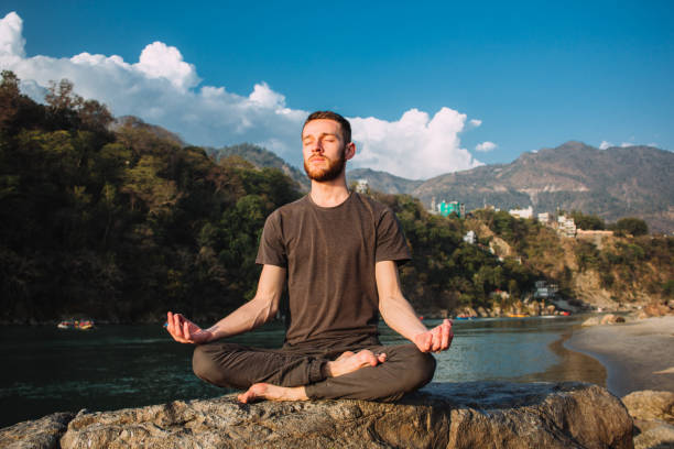 istock A young man meditates in a lotus position with closed eyes over the Ganges river in Rishikesh. 1178353874