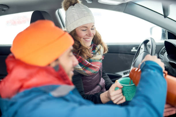 Smiling diverse couple holding Christmas presents while walking through a winter forest