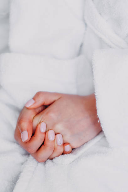 istock Caucasian ladies hands clasped with pink paint nails in a bathrobe close up. The bride does her makeup. 1178357537