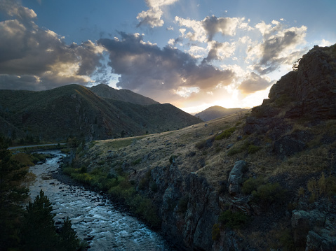 View of winding river and mountain canyon. Shot looking towards sun at dusk