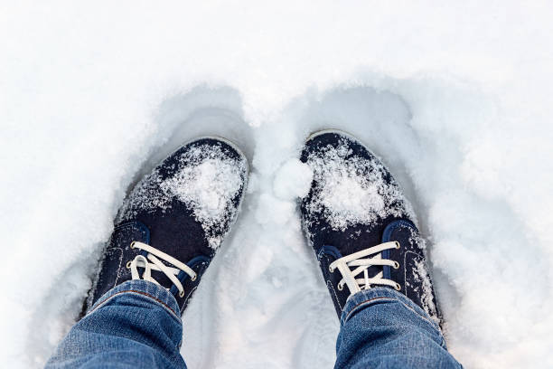 blaue turnschuhe auf schnee. ein blick von oben. sportschuhe top-ansicht. - snow track human foot steps stock-fotos und bilder