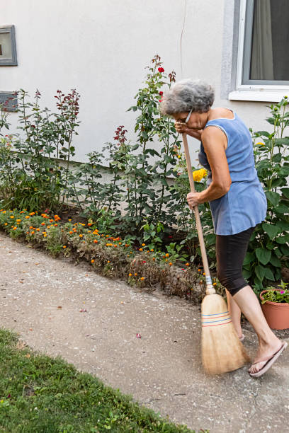 istock Senior Woman is Sweeping the Backyard with Broom 1178366245