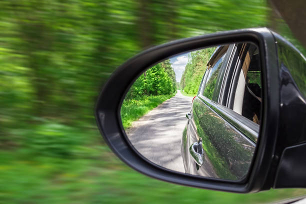 uma vista no espelho de vista lateral. espelho do carro traseiro. reflexão da estrada no movimento - rear view mirror car mirror sun - fotografias e filmes do acervo