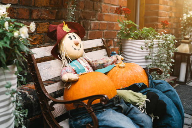 A rag scarecrow and two pumpkins in jeans are sitting on a bench.
