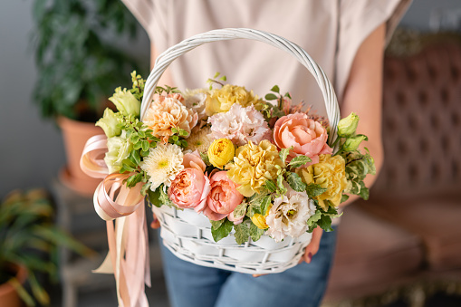 Flower arrangement in Wicker basket. Beautiful bouquet of mixed flowers in woman hand. Floral shop concept . Handsome fresh bouquet. Flowers delivery.