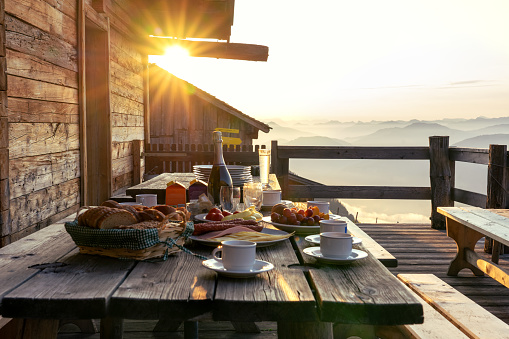 Breakfast table in rustic wooden terace patio of a hut hutte in Tirol alm at sunrise