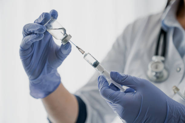 medication nurse wearing protective gloves get a needle ready for an injection - injetar imagens e fotografias de stock