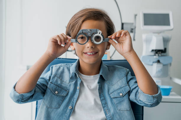 young boy undergoing eye test with spectacles in medical clinic - patient happiness cheerful optometrist imagens e fotografias de stock