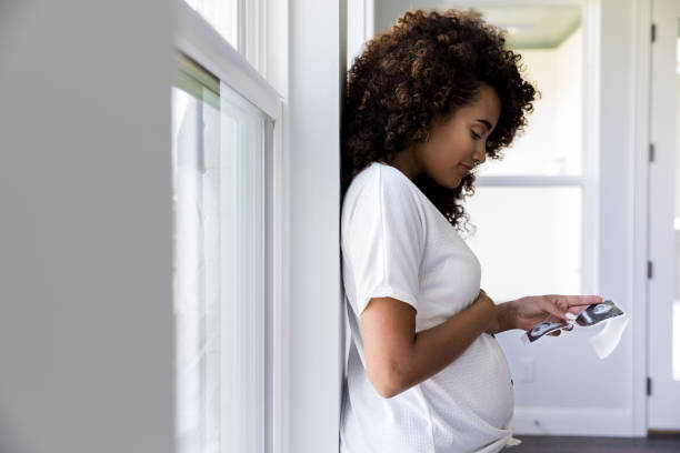 профиль вид беременной женщины, глядя на ультразвуковые фотографии - window human pregnancy home interior women стоковые фото и изображения