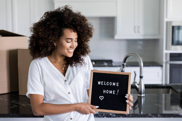 kobieta posiada tablicę z komunikatem "welcome home" - human pregnancy finance mixed race person holding zdjęcia i obrazy z banku zdjęć