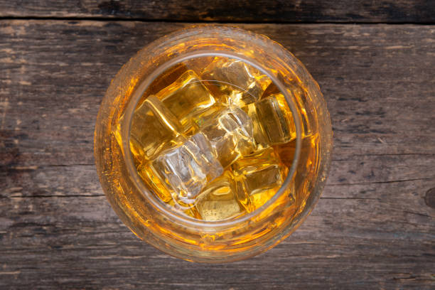 istock whiskey in glass with ice on wooden table on black background 1178381471