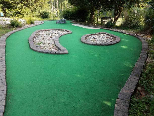 miniature golf course hole with green artificial grass and stones