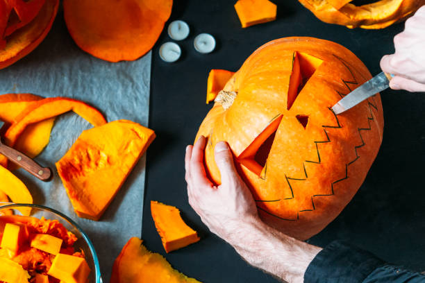 istock A man carves a pumpkin lantern Jack on a black table, Halloween decorations ,top view 1178382326
