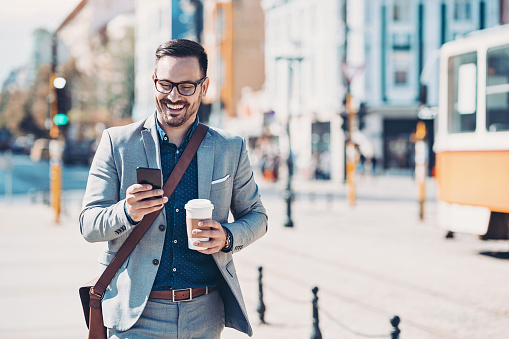 Smiling businessman texting outdoors in the city