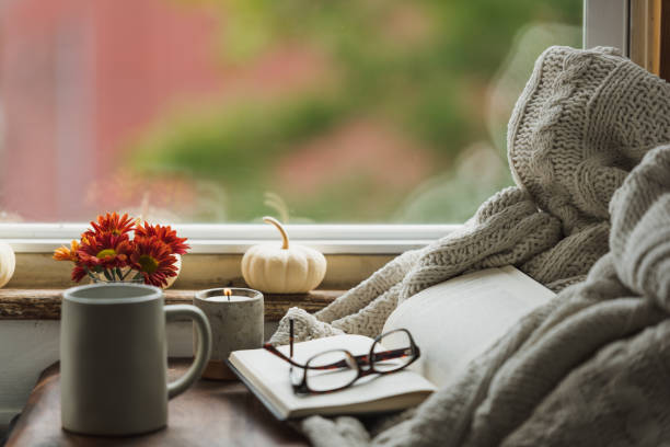 A nice warm looking reading nook in the fall that conveys the idea of being comfortable at home in autumn with a cup of coffee or tea and reading a good book.