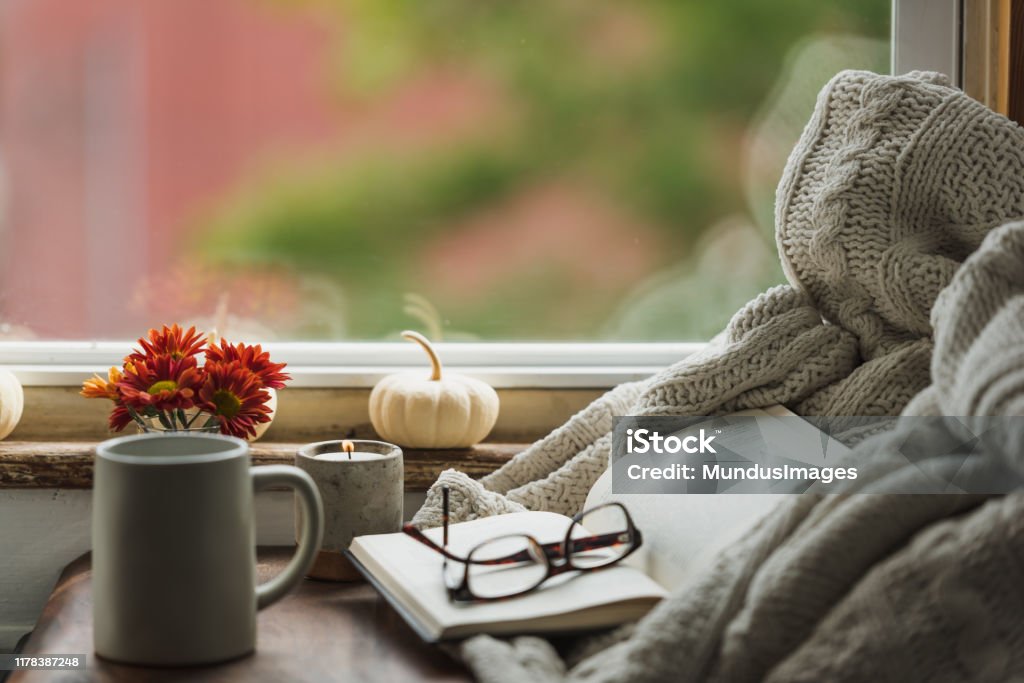 A cozy reading nook in the fall with a blanket and coffee A nice warm looking reading nook in the fall that conveys the idea of being comfortable at home in autumn with a cup of coffee or tea and reading a good book. Autumn Stock Photo