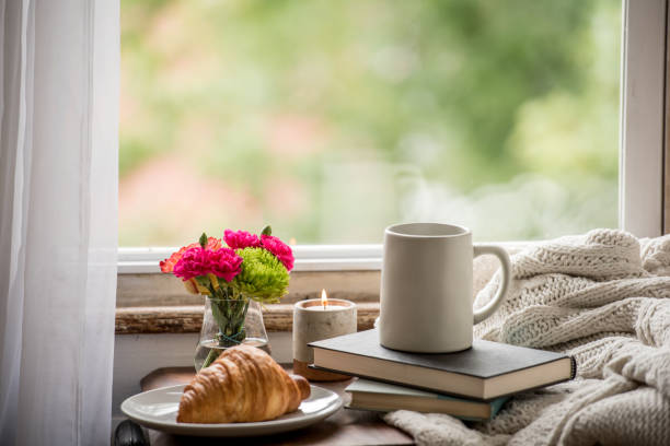 Warm and cozy at home reading a book and drinking coffee A comfortable reading nook with a croissant and coffee or tea and a book to cuddle up in a blanket and read. hygge photos stock pictures, royalty-free photos & images