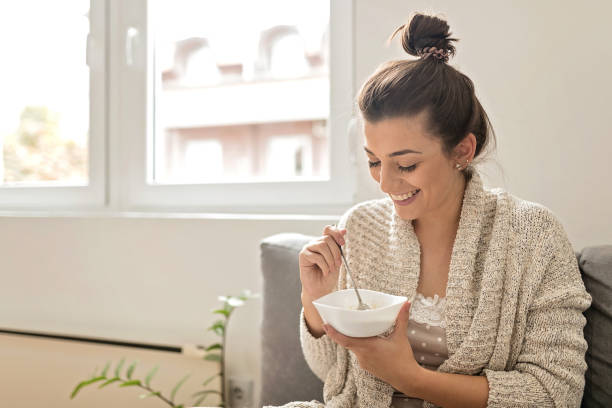 woman eating an oatmeal - eating women breakfast cereal imagens e fotografias de stock