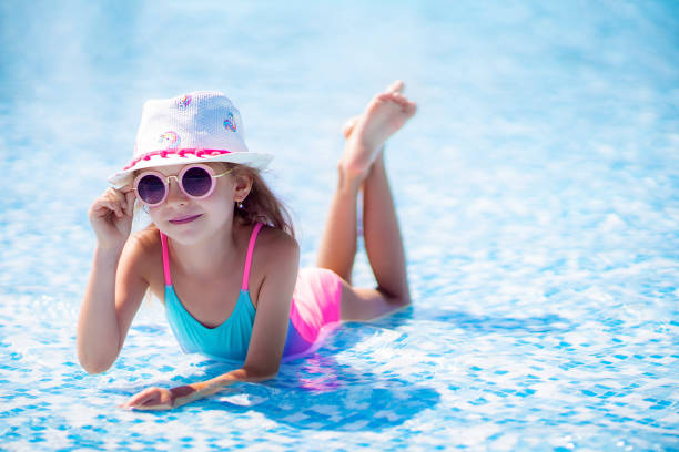 dziewczynka w okularach przeciwsłonecznych i kapelusz z jednorożcem w odkrytym basenie luksusowego kurortu na wakacjach na tropikalnej wyspie plaży - inflatable ring zdjęcia i obrazy z banku zdjęć