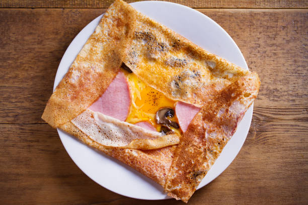 crepes, panqueques finos con jamón, queso, huevo y champiñones. panqueques con relleno en plato blanco - galette fotografías e imágenes de stock