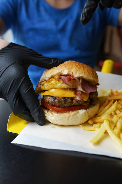 istock Hand taking a delicious burger with pineapple and bacon, ready to be enjoyed 1178425208