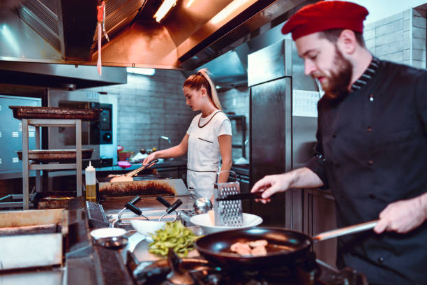istock Male Cook Preparing Meat While Female Colleague Makes Bread Toast 1178425586